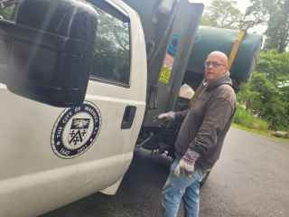 Illustration de l'article : Un homme se dirige vers un camion à ordures avec une boîte en carton avant d'entendre des miaulements à l'intérieur